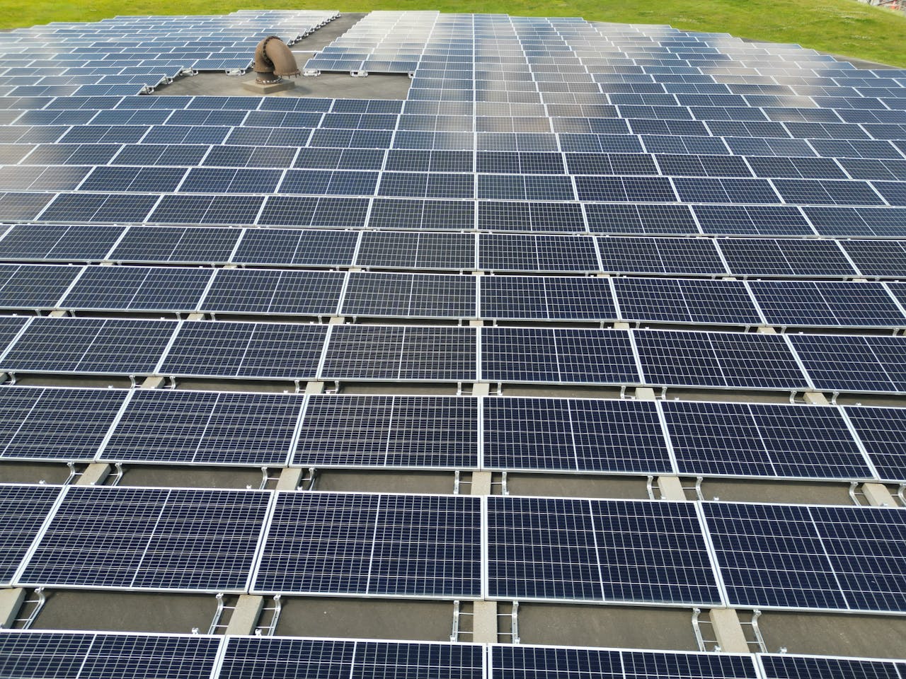 services-03 A large solar panel array on a sunny day in an open green field.
