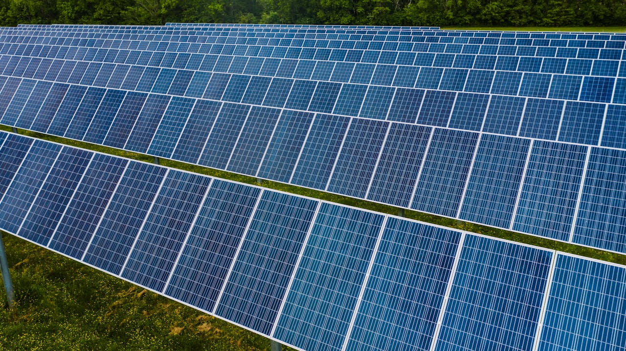 services-01 High angle pole mounted solar energy trackers installed on green field in solar power station